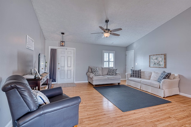 living room featuring lofted ceiling, wood finished floors, baseboards, and a textured ceiling