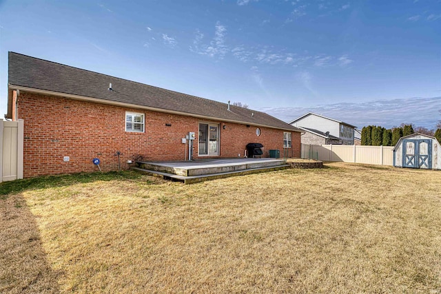 back of property featuring brick siding, fence, a shed, a yard, and an outbuilding