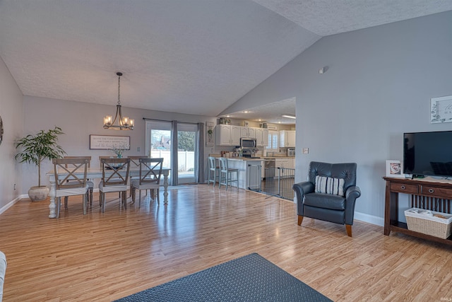 interior space with baseboards, high vaulted ceiling, light wood-type flooring, a notable chandelier, and a textured ceiling