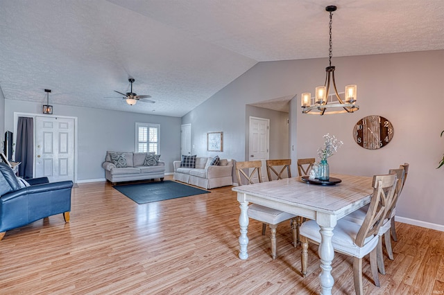 dining space featuring light wood-type flooring, baseboards, a textured ceiling, and vaulted ceiling