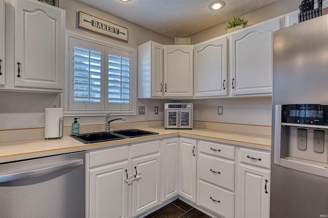 kitchen with a sink, a textured ceiling, white cabinetry, appliances with stainless steel finishes, and light countertops