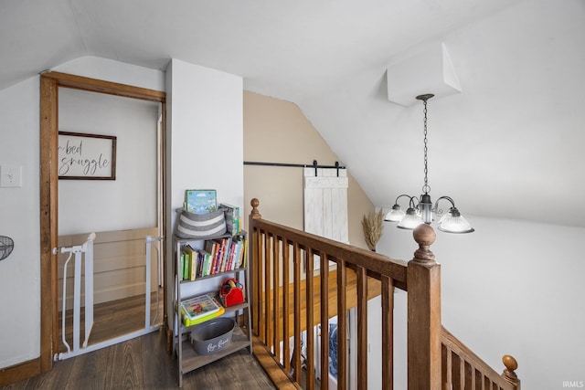 corridor featuring dark wood finished floors, lofted ceiling, an upstairs landing, and an inviting chandelier