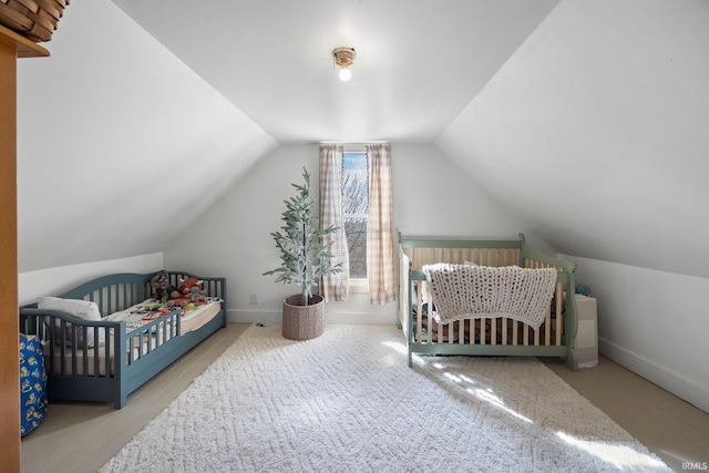 bedroom featuring a crib, baseboards, and lofted ceiling