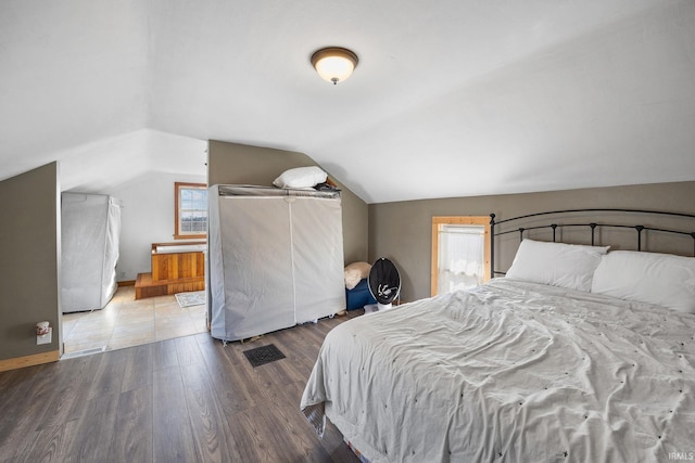 bedroom featuring wood finished floors, baseboards, and vaulted ceiling