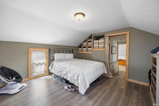 bedroom with vaulted ceiling, baseboards, and dark wood-style flooring