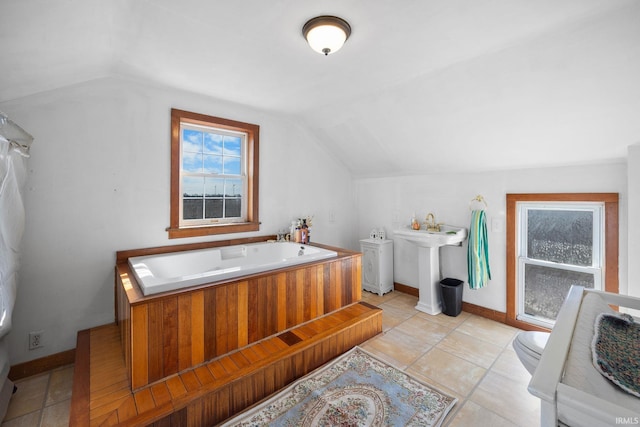 bathroom featuring toilet, a sink, baseboards, a bath, and vaulted ceiling