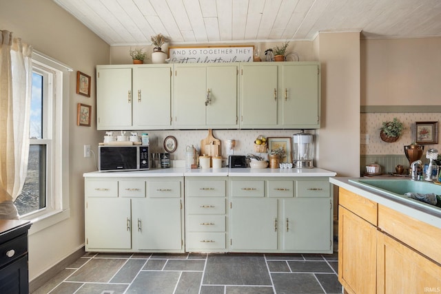 kitchen featuring stainless steel microwave, wood ceiling, light countertops, and a sink