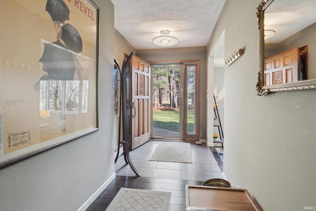 foyer entrance with baseboards, a textured ceiling, and wood finished floors