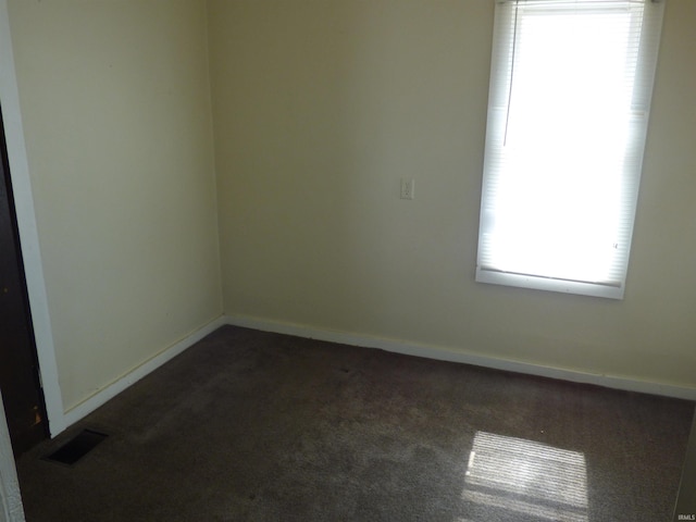 unfurnished room featuring baseboards, visible vents, and dark colored carpet