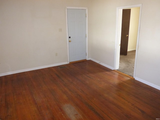 empty room featuring visible vents, baseboards, and hardwood / wood-style floors