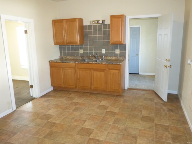 kitchen with a sink, baseboards, and backsplash