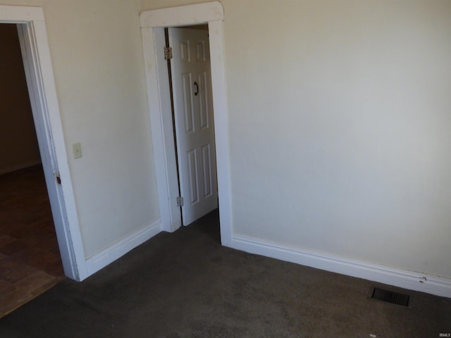 unfurnished room featuring baseboards, visible vents, and dark colored carpet