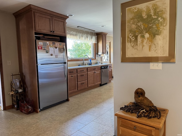 kitchen with appliances with stainless steel finishes, pendant lighting, light countertops, and a sink