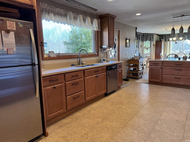 kitchen featuring a sink, light countertops, appliances with stainless steel finishes, decorative light fixtures, and brown cabinets