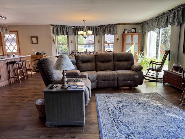 living room with plenty of natural light, dark wood-type flooring, and a chandelier