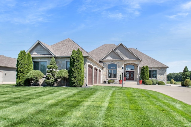 view of front of property featuring a garage, stone siding, roof with shingles, and a front lawn