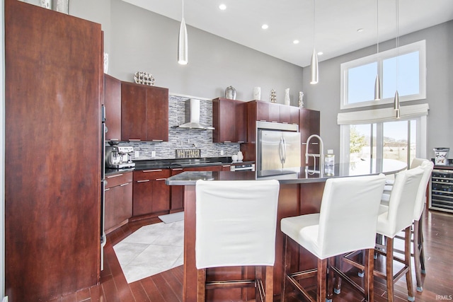 kitchen featuring dark countertops, wall chimney exhaust hood, modern cabinets, and stainless steel fridge