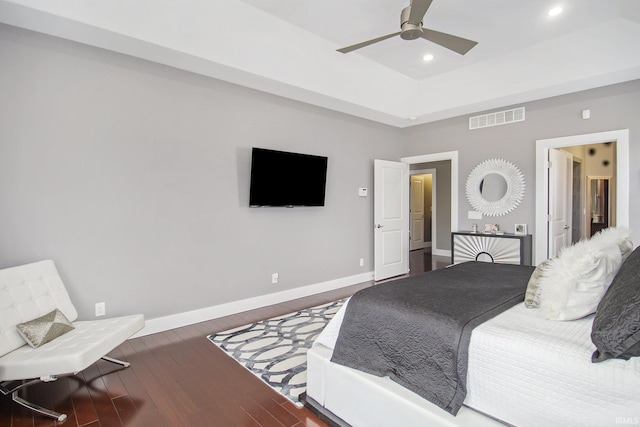 bedroom featuring visible vents, a raised ceiling, wood finished floors, recessed lighting, and baseboards