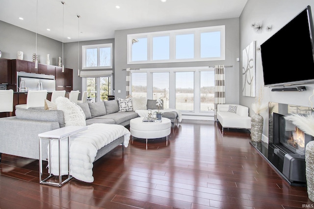 living room featuring a fireplace, a high ceiling, and dark wood-style floors