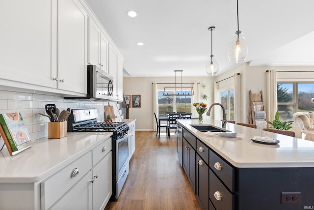 kitchen with a sink, backsplash, stainless steel appliances, white cabinets, and light countertops