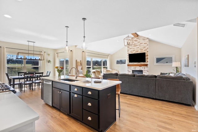 kitchen featuring visible vents, light wood finished floors, a sink, light countertops, and dishwasher