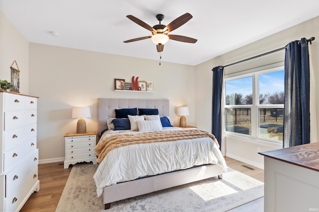 bedroom featuring visible vents, a ceiling fan, light wood-type flooring, and baseboards