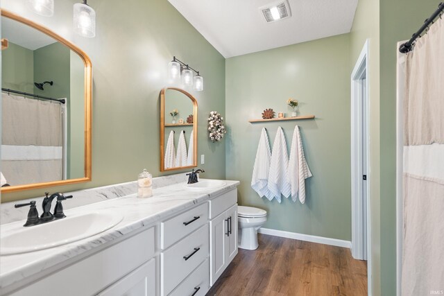 bathroom with double vanity, wood finished floors, visible vents, and a sink