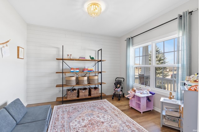 living area with baseboards, wooden walls, and wood finished floors