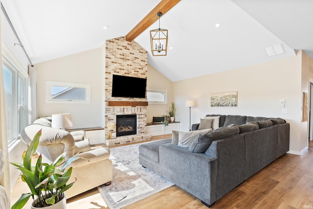 living room with a brick fireplace, a chandelier, beamed ceiling, wood finished floors, and high vaulted ceiling