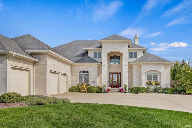 french country home featuring brick siding, a front lawn, concrete driveway, roof with shingles, and an attached garage