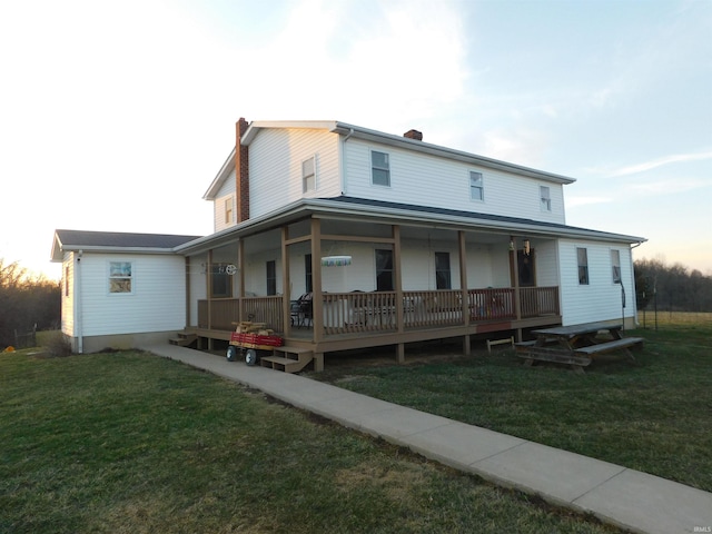 rear view of property with a yard and covered porch