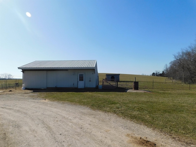 view of pole building featuring a rural view, a lawn, and fence