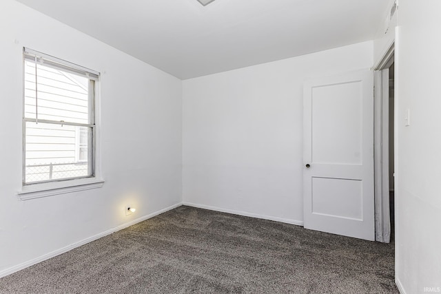 unfurnished room featuring dark colored carpet, visible vents, and baseboards