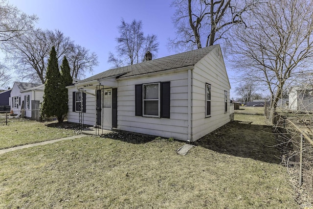 view of front of property featuring a shingled roof, a front yard, fence, and a chimney