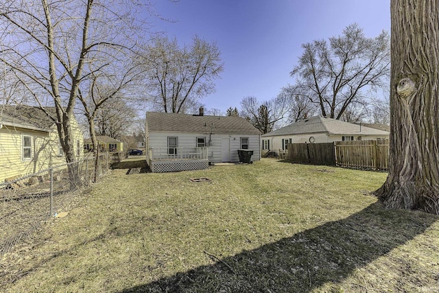 rear view of house featuring a lawn, a wooden deck, and a fenced backyard