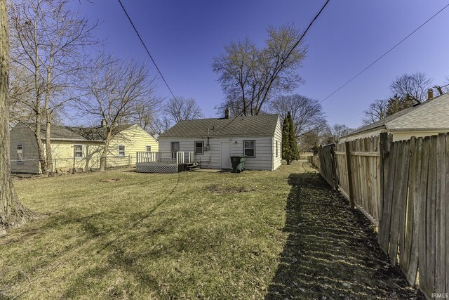 back of house with a fenced backyard, a wooden deck, and a yard