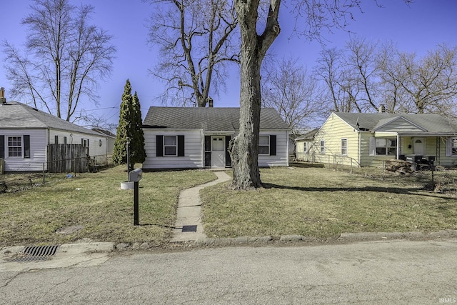 view of front facade with roof with shingles, a front lawn, and fence