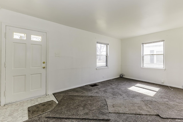 foyer entrance featuring visible vents, carpet flooring, and baseboards