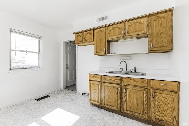 kitchen featuring light countertops, brown cabinets, visible vents, and a sink