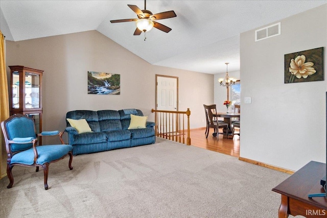 carpeted living room featuring visible vents, ceiling fan with notable chandelier, baseboards, and vaulted ceiling