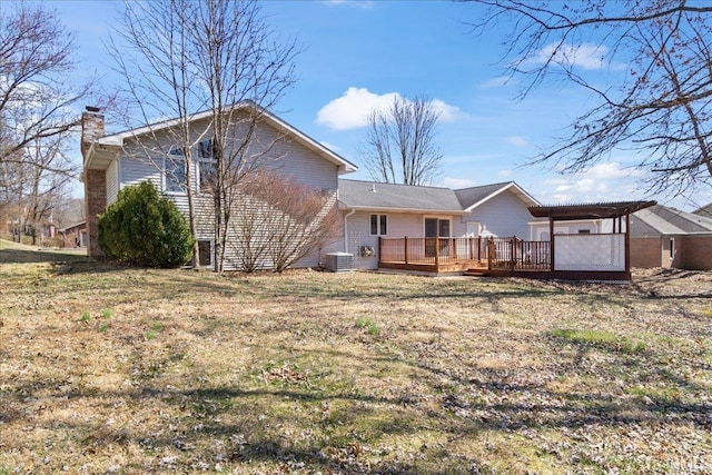 rear view of house with a wooden deck, a yard, central AC, and a chimney