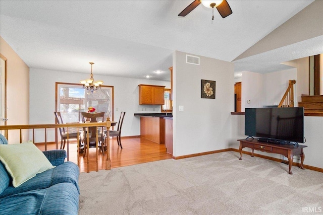 living area featuring baseboards, visible vents, lofted ceiling, light carpet, and ceiling fan with notable chandelier