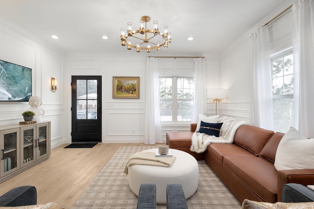 living area featuring crown molding, a decorative wall, and light wood-type flooring