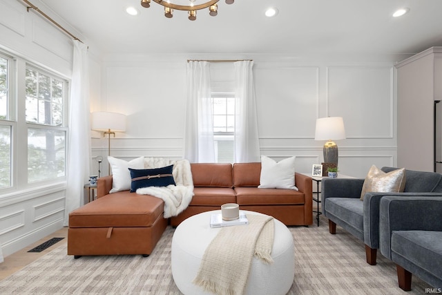 living room featuring a decorative wall, recessed lighting, and visible vents