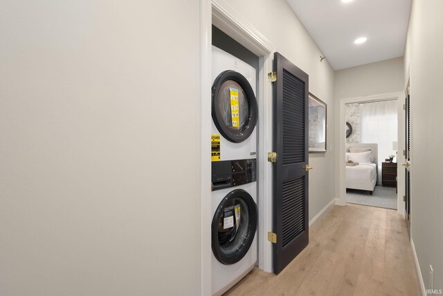 laundry room featuring wood finished floors, baseboards, laundry area, recessed lighting, and stacked washer and clothes dryer