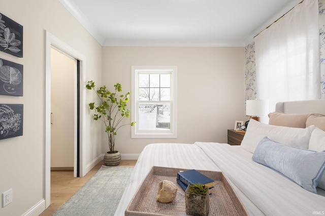 bedroom with baseboards, light wood-style floors, and ornamental molding