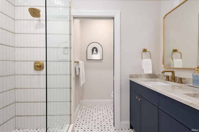 full bath featuring double vanity, baseboards, a tile shower, and a sink