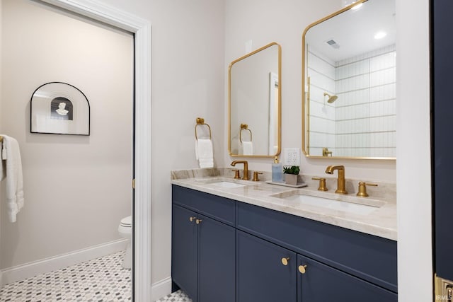 bathroom with a sink, baseboards, toilet, and double vanity