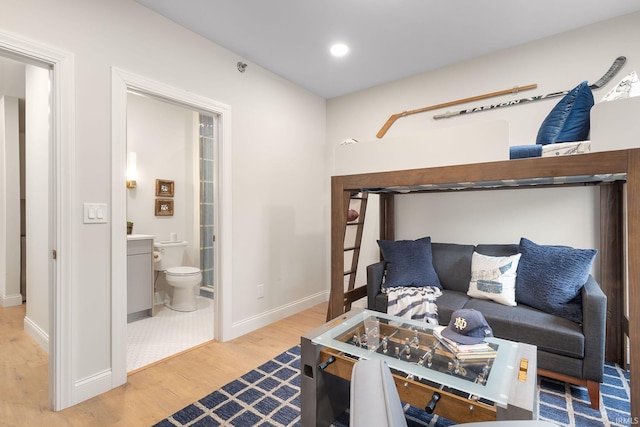 bedroom with recessed lighting, ensuite bath, baseboards, and wood finished floors