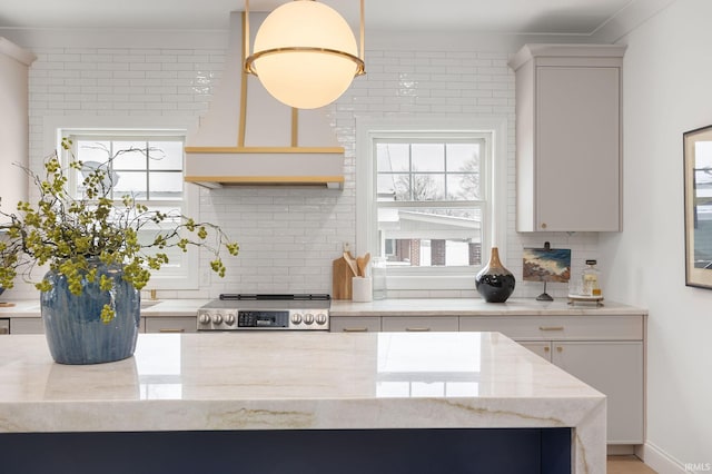 kitchen featuring light stone counters, decorative backsplash, stainless steel electric stove, and custom range hood